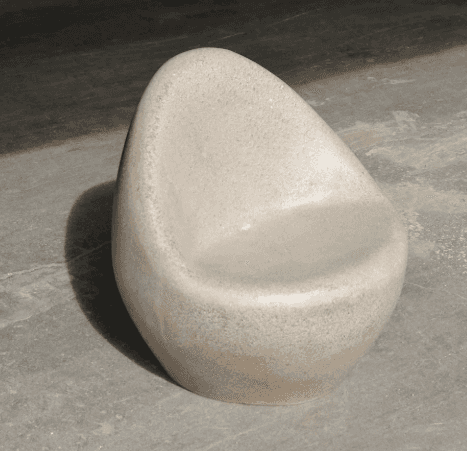 A single, smooth, stone-like chair with a rounded, organic shape. The chair features a scooped seat… — free GLTF 3D model