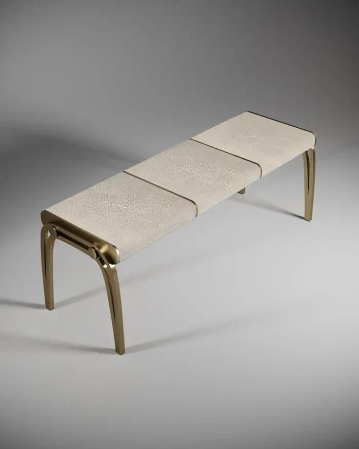 A contemporary bench featuring a brass frame and light-colored shagreen upholstery, segmented into three sections. The legs are elegantly curved, and the overall design suggests a luxurious aesthetic. — 3D model