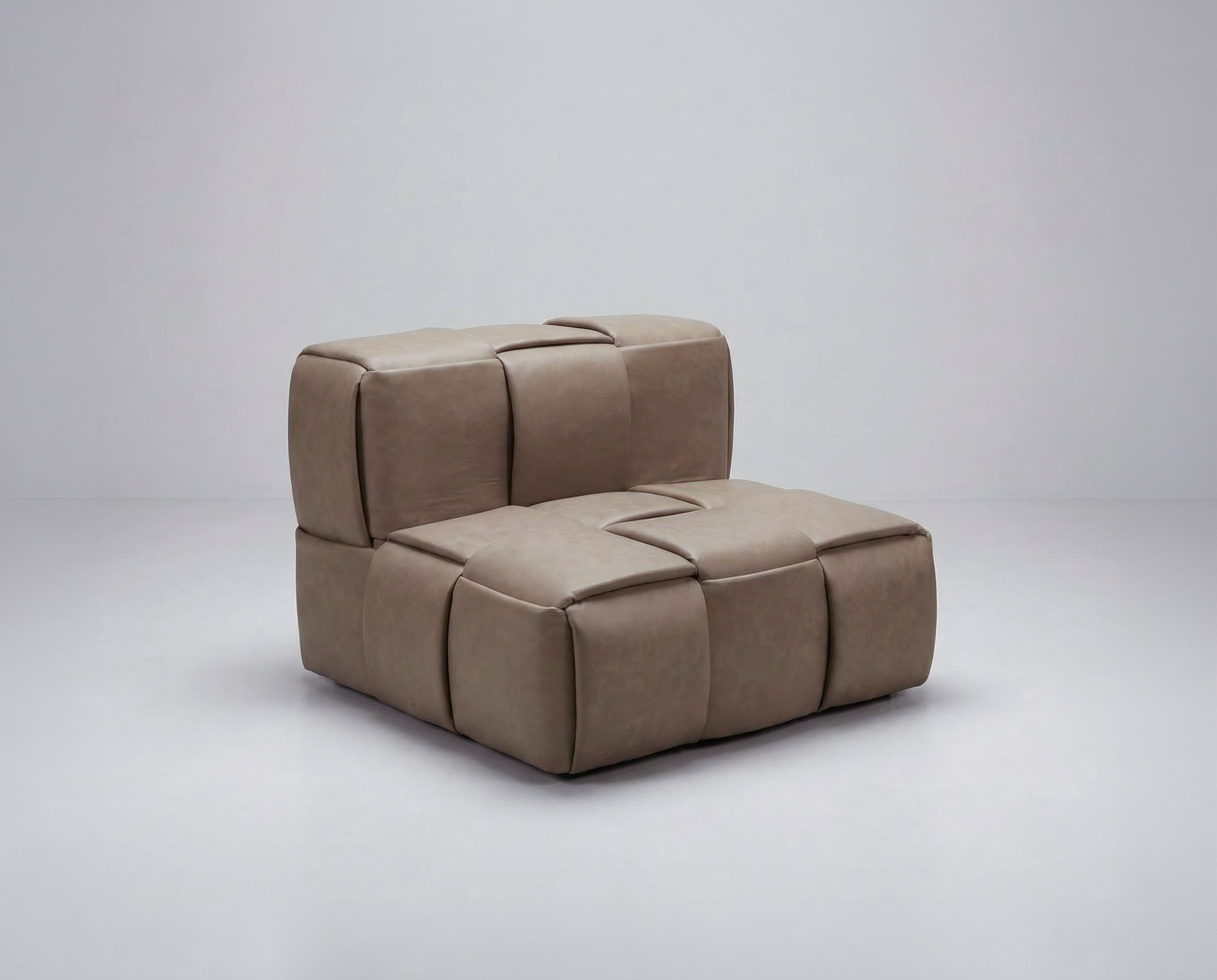 A modular armchair with a low profile and cushioned seating. The piece is characterized by its woven or quilted exterior, creating a series of padded segments. It appears to be upholstered in a soft material, possibly leather or a high-quality faux leather. The design is contemporary and minimalist, with clean lines and a focus on comfort and texture. — 3D model