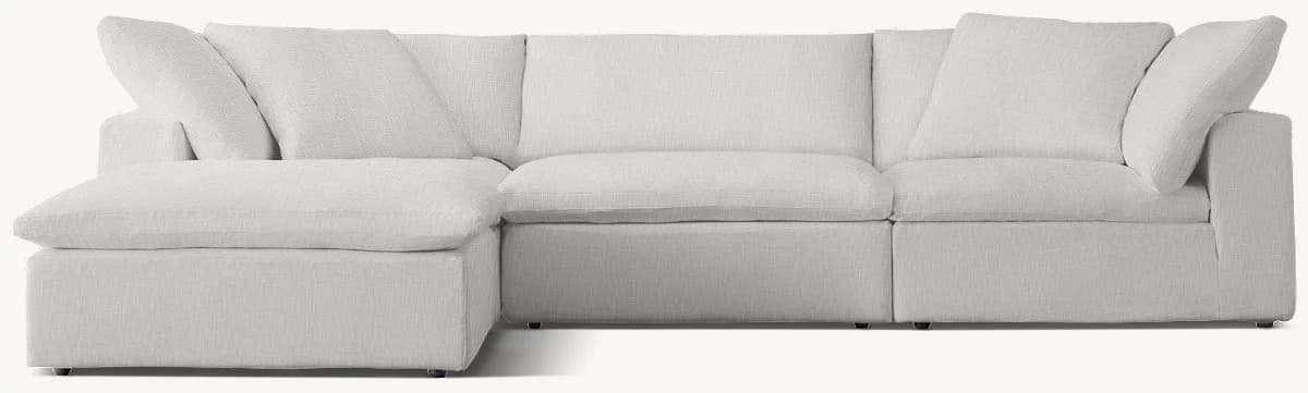 A light grey modular sectional sofa featuring deep seating and a relaxed, plush aesthetic. It comprises a left-hand chaise lounge unit and two armless sofa sections, arranged to form an L-shaped configuration. The sofa is fully upholstered in a textured fabric, with soft, oversized back cushions and thick seat cushions, all designed for maximum comfort. — 3D model