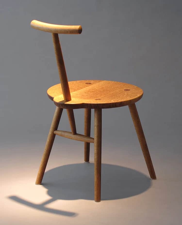 A wooden chair with a round seat and a single backrest support. The chair has four legs, with two le… — free GLTF 3D model