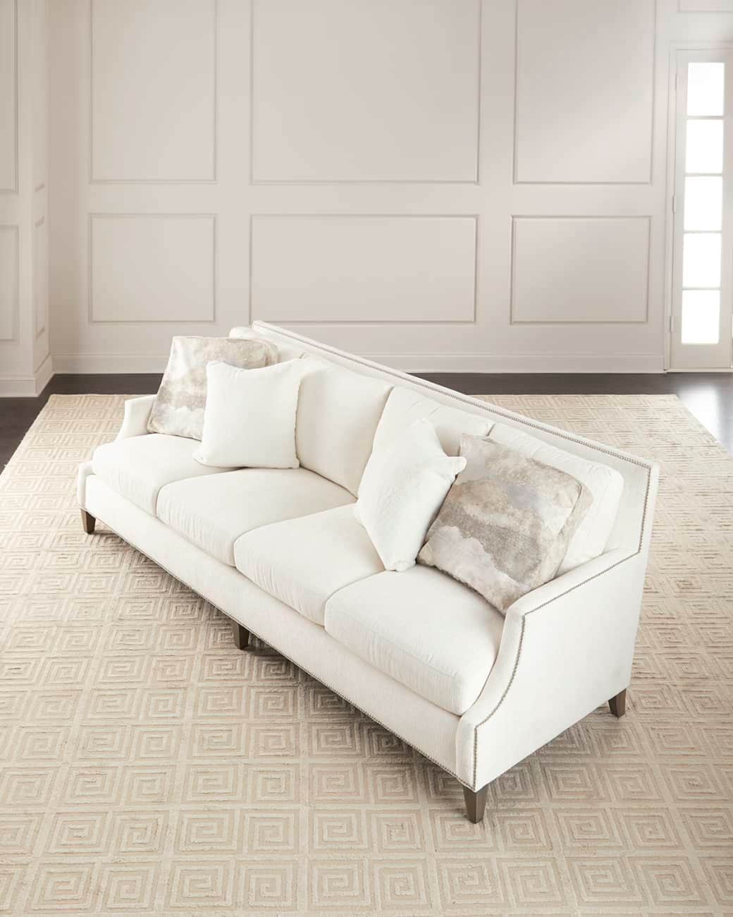 A white upholstered three-seater sofa with curved arms and decorative nailhead trim along the edges… — free GLTF 3D model