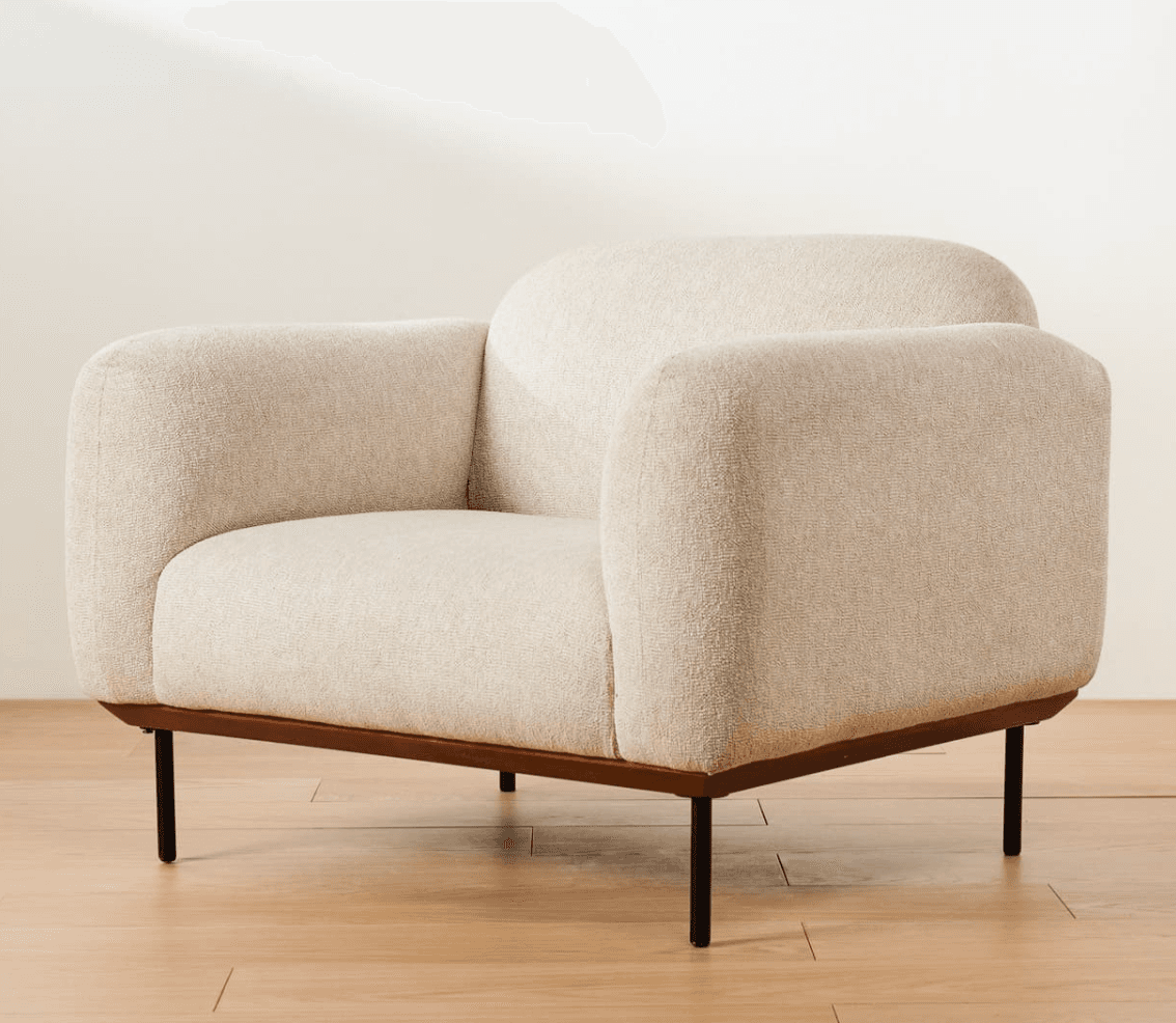 A modern armchair with a textured, light-colored fabric upholstery. The armchair features a rounded silhouette with integrated armrests and a high, curved backrest. It is supported by a dark, slim rectangular frame and four slender, tapered black legs. — 3D model