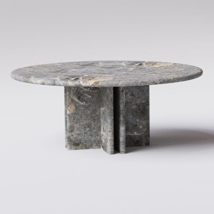 A round coffee table with a thick, solid top and a substantial pedestal base. The base appears to be constructed from multiple vertical slabs that meet at an intersection, creating a robust and architectural form. The material exhibits a natural veining pattern typical of stone. — 3D model