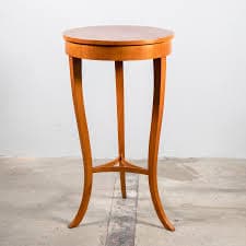 A tall, slender pedestal table with a circular top and three curved legs that meet at a central support. — 3D model