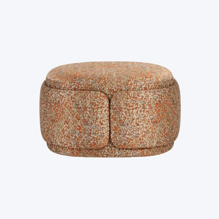 A round, upholstered storage ottoman featuring a rich, intricate pattern primarily in shades of orange, cream, and blue. The ottoman has a distinct two-part top, suggesting an internal storage compartment. Its base is subtly recessed, giving it a slightly floating appearance. The fabric's design combines floral or botanical elements with geometric motifs. — 3D model