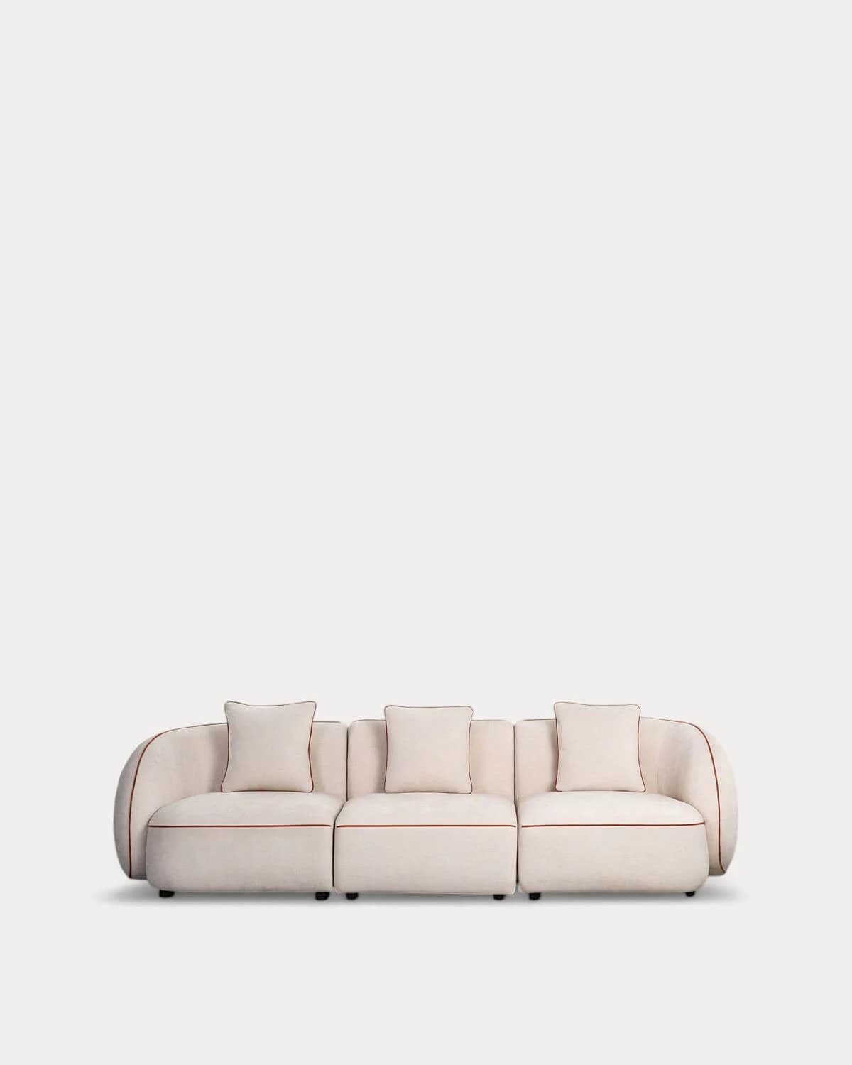 A three-seat modular sofa with a soft, rounded contemporary design, upholstered in a light-colored fabric with reddish-brown contrast piping. It features three matching square throw pillows. — 3D model