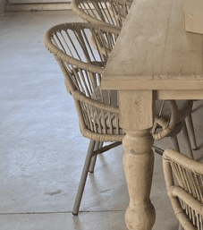 A contemporary dining armchair featuring a tightly woven rope seat and a curved backrest formed by vertical rope-wrapped slats with integrated armrests. It stands on four slender, angled metal legs in a matte finish. The entire chair is rendered in a neutral beige or light brown color. — 3D model
