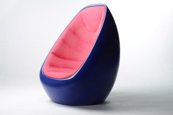 A modern armchair with a distinctive egg-like shape. The exterior shell is a deep, glossy navy blue, contrasting with the plush, padded interior upholstered in a vibrant pink fabric. The interior features segmented cushioning that follows the curvature of the chair, providing a comfortable seating experience. The design is organic and sculptural, with a smooth, continuous form. — 3D model