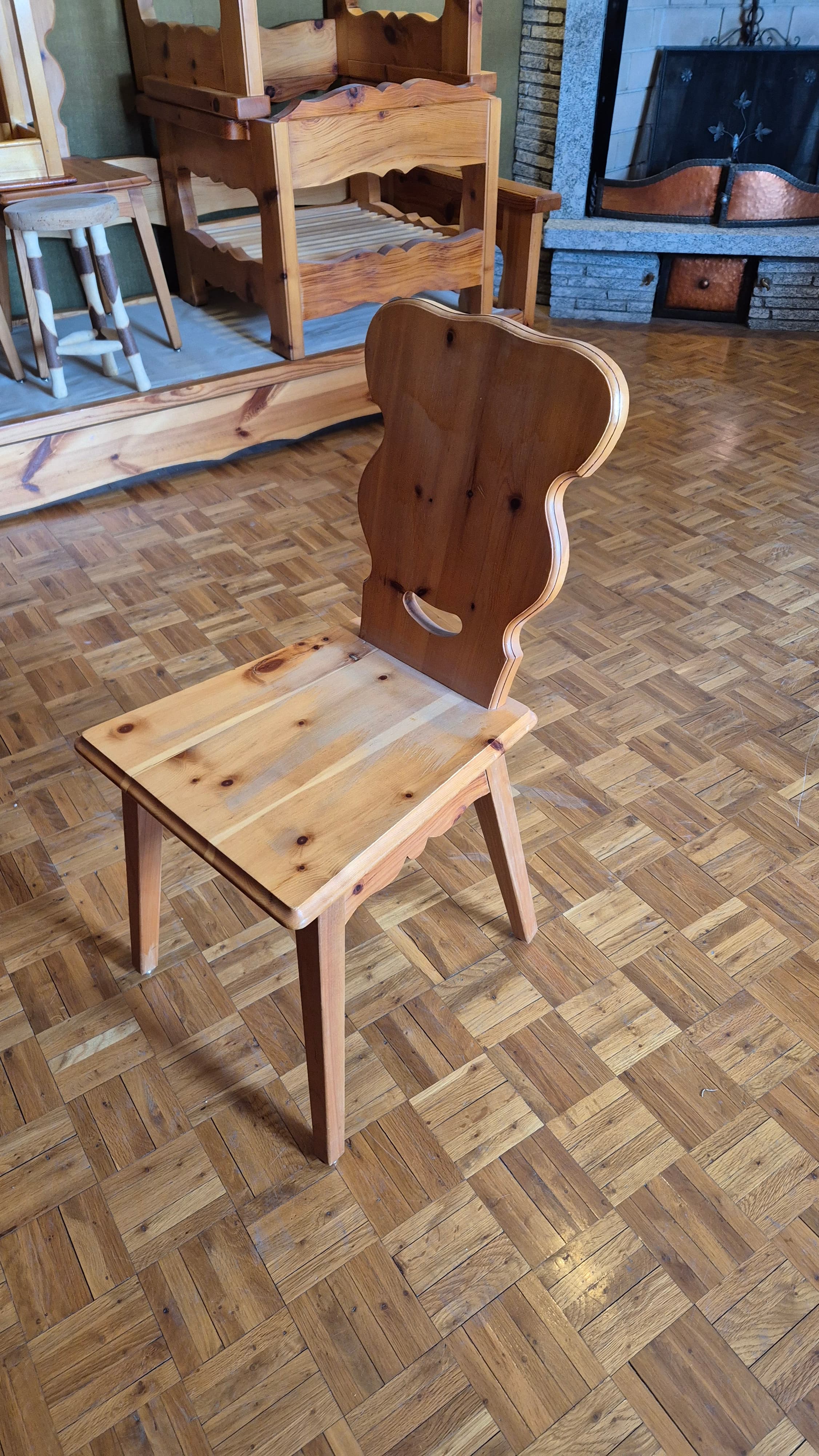A wooden chair with a carved backrest and a seat made of several planks. The chair has four legs, with the back legs extending upwards to form the support for the backrest. The design suggests a rustic or folk style. — 3D model