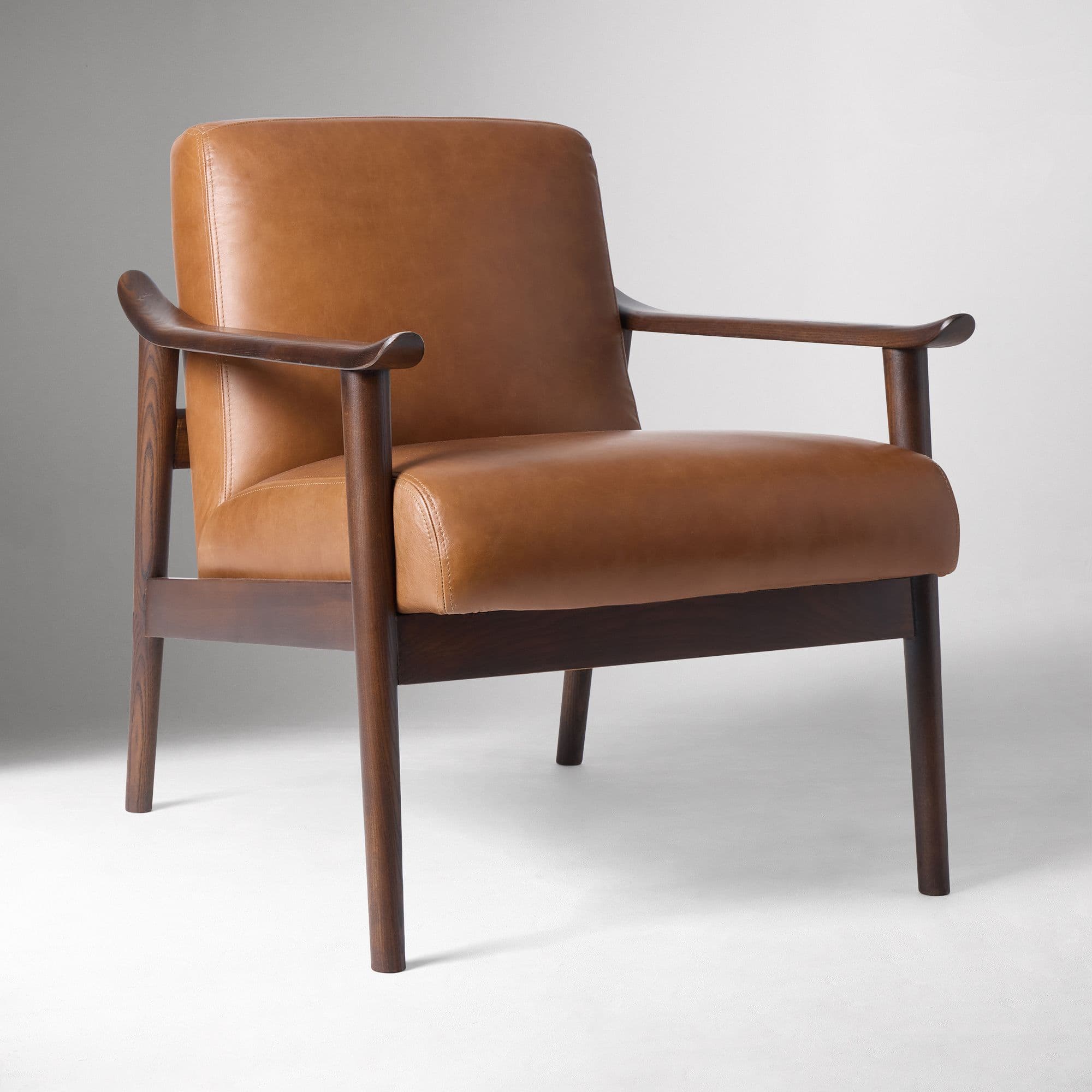 A Mid-Century Modern style lounge chair featuring a sturdy dark wood frame and plush, cognac-colored leather upholstery. — 3D model