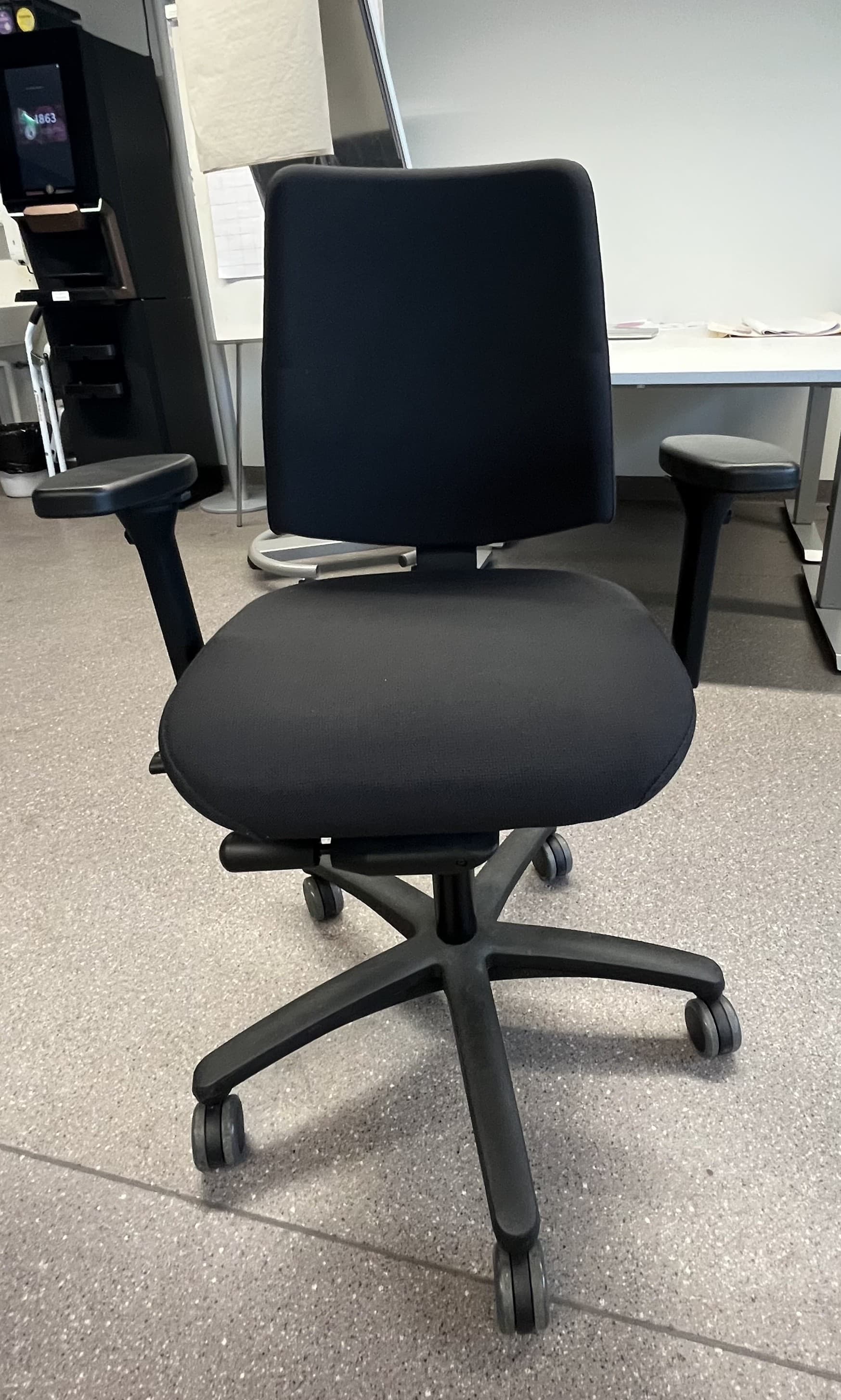 A modern office chair featuring black fabric upholstery on both the seat and backrest. It has a five-star swivel base made of black plastic, equipped with caster wheels for mobility. The chair includes black plastic armrests that appear to be adjustable. The design is functional and contemporary, suitable for various office or home workspace environments. — 3D model