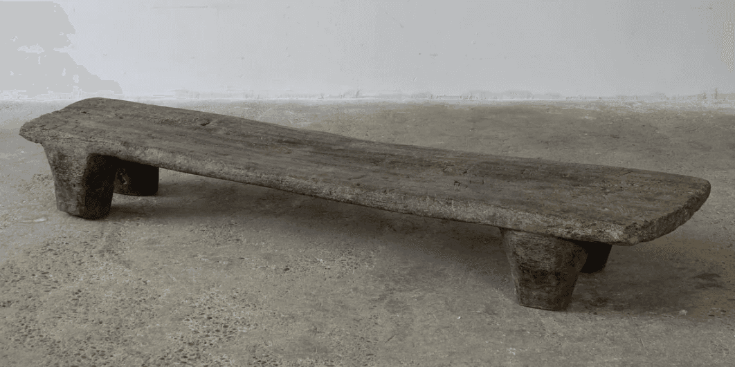 A rustic, low-profile bench with a flat, elongated top and two substantial, block-like legs at each… — 3D model