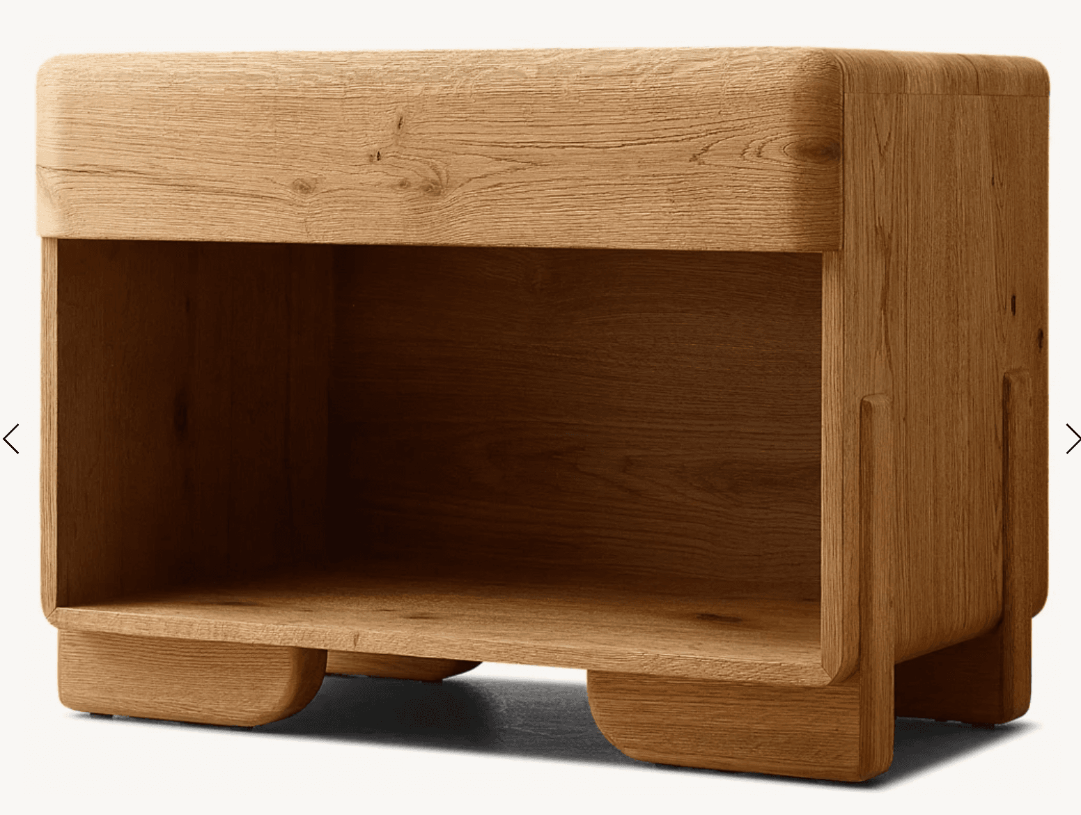 A small, solid oak wood nightstand featuring smoothly rounded corners and edges, an integrated open storage shelf, and standing on four subtly curved, integrated feet. The natural wood grain is clearly visible across all surfaces. — 3D model