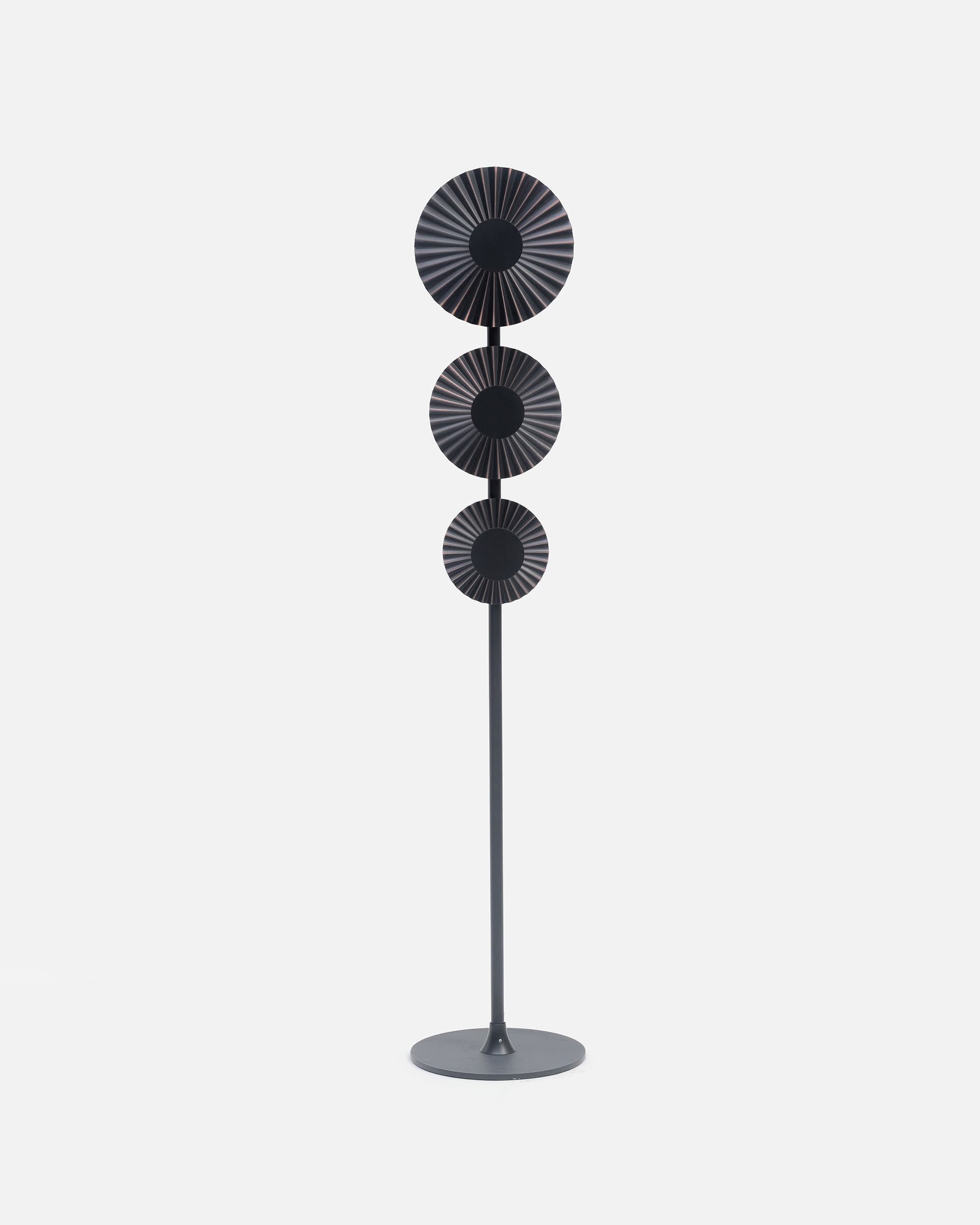 A tall, contemporary floor lamp featuring a round base, a slender central pole, and three circular, radially fluted or ridged elements stacked vertically. The lamp has a dark, possibly bronzed or dark grey, metallic finish with subtle lighter metallic highlights on the ridges of the circular elements. — 3D model