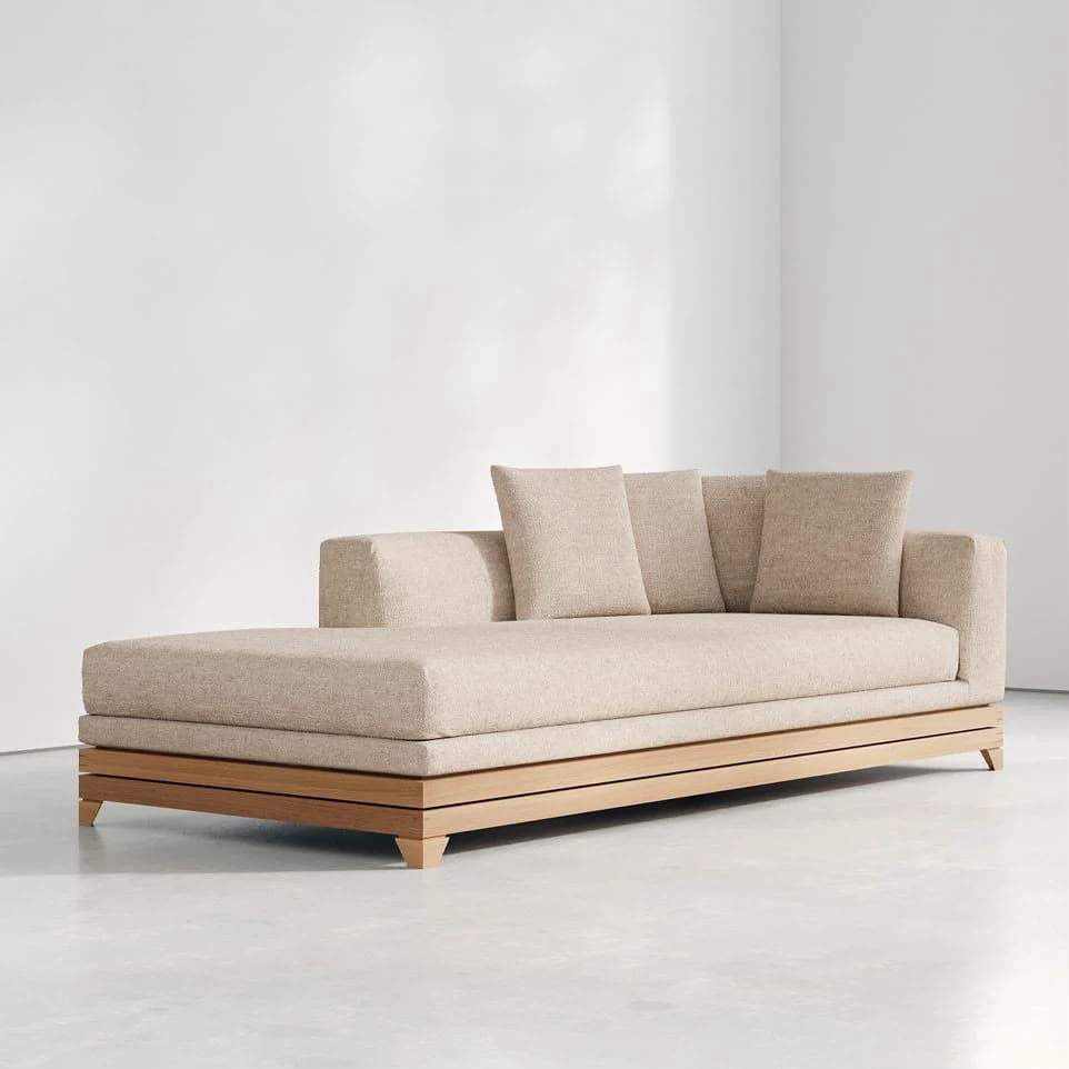 A contemporary chaise lounge featuring a low-profile design, upholstered in a textured beige fabric, with a visible light-toned wooden slatted base and loose back cushions. — 3D model