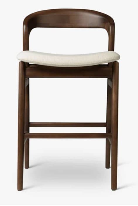 A wooden bar stool with a curved backrest and a cushioned seat. The stool features four tapered legs connected by stretchers for stability. The construction appears to be solid wood with a dark stain finish. — 3D model