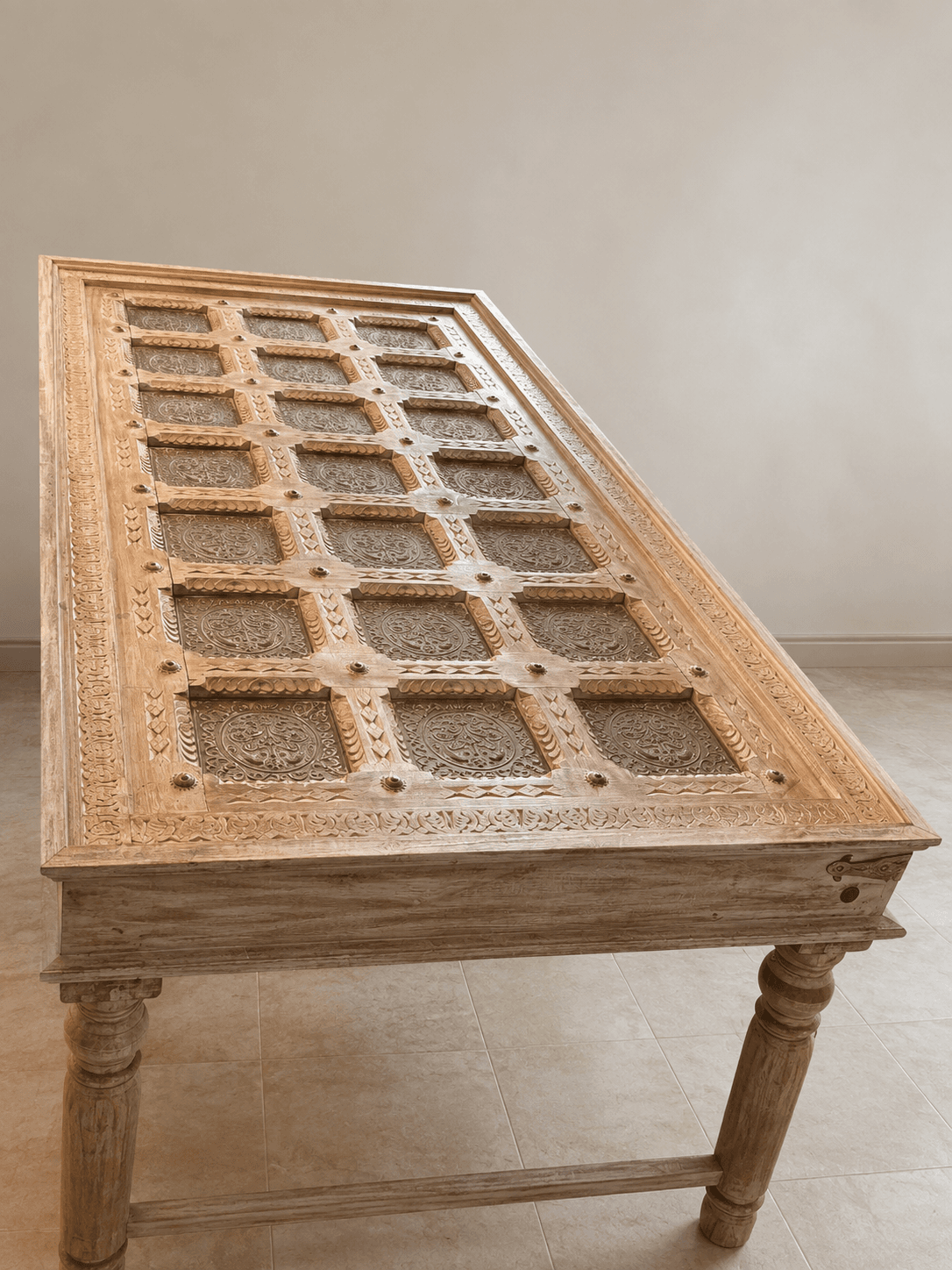 A rectangular coffee table crafted from light-toned wood, featuring extensively carved details on its frame and legs. The tabletop is segmented into a grid pattern, with each square section containing an ornate metal grille insert. The table stands on four turned legs connected by a stretcher bar, exhibiting a traditional or ethnic design aesthetic. — 3D model