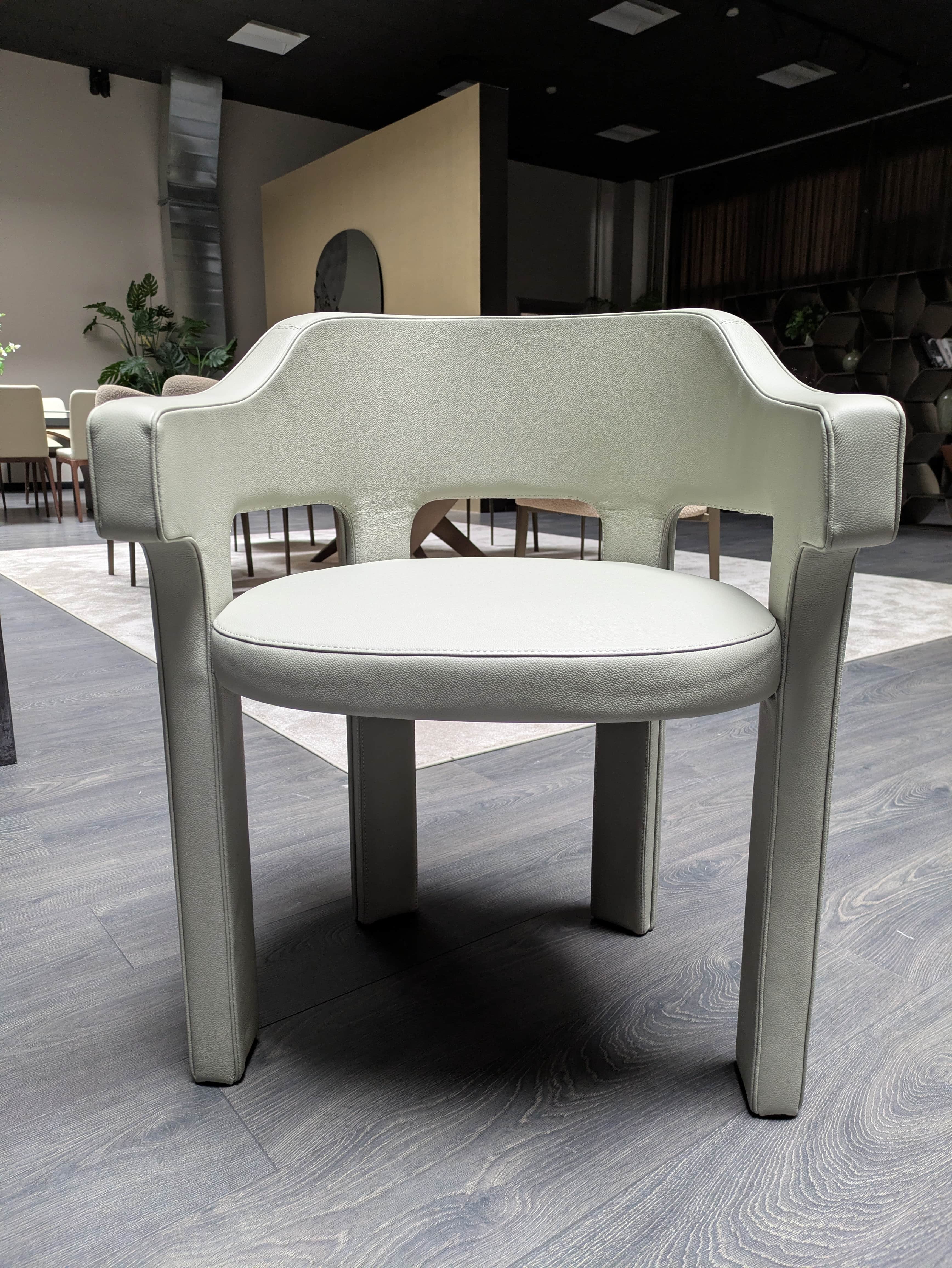 A modern armchair fully upholstered in light grey, pebbled faux leather or leather. It features a di… — free BLEND 3D model