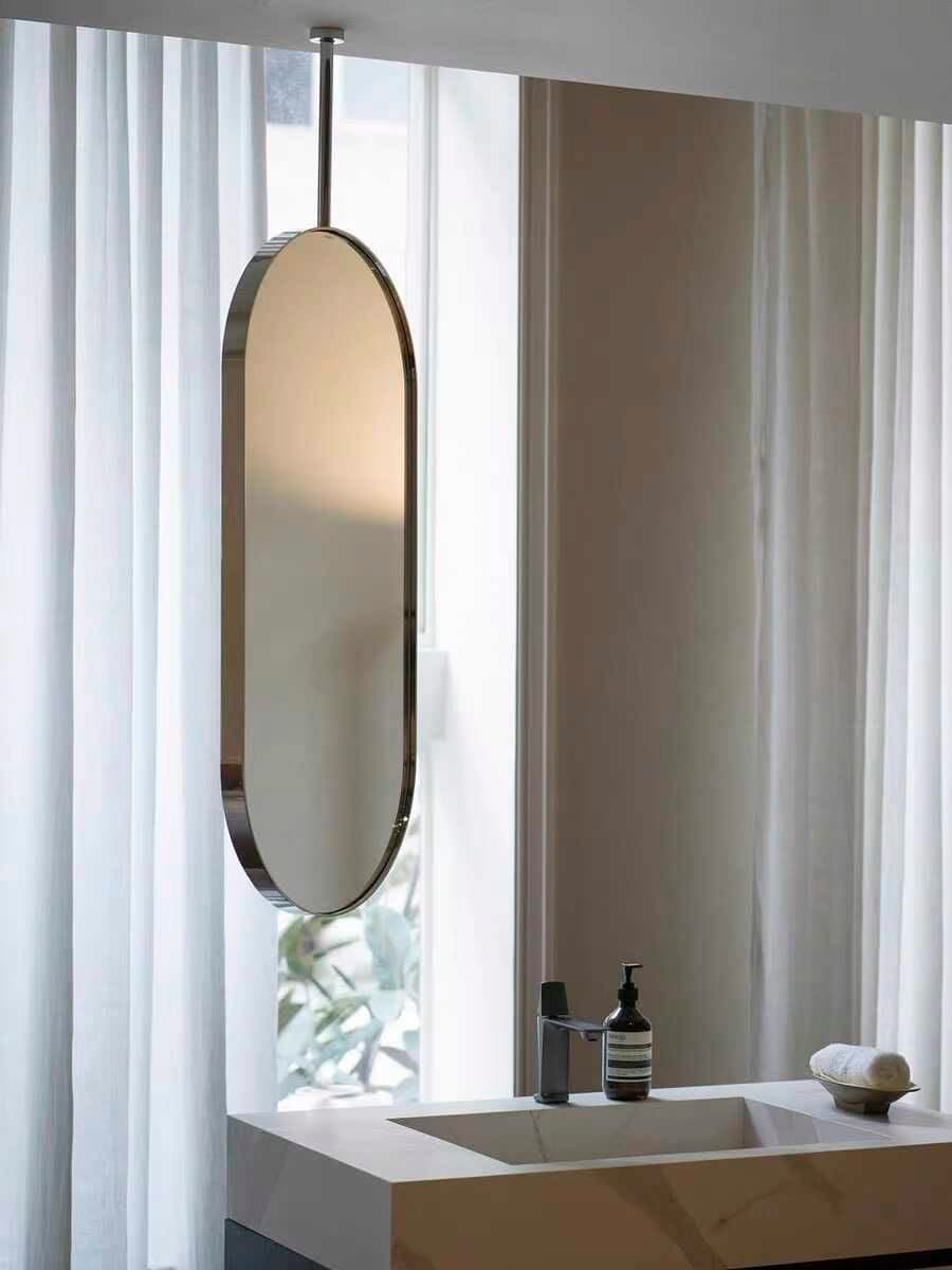 A tall, oval-shaped mirror featuring a polished metal frame, suspended vertically by a slender rod from the top. The design is sleek and minimalist, with smooth, rounded edges. — 3D model