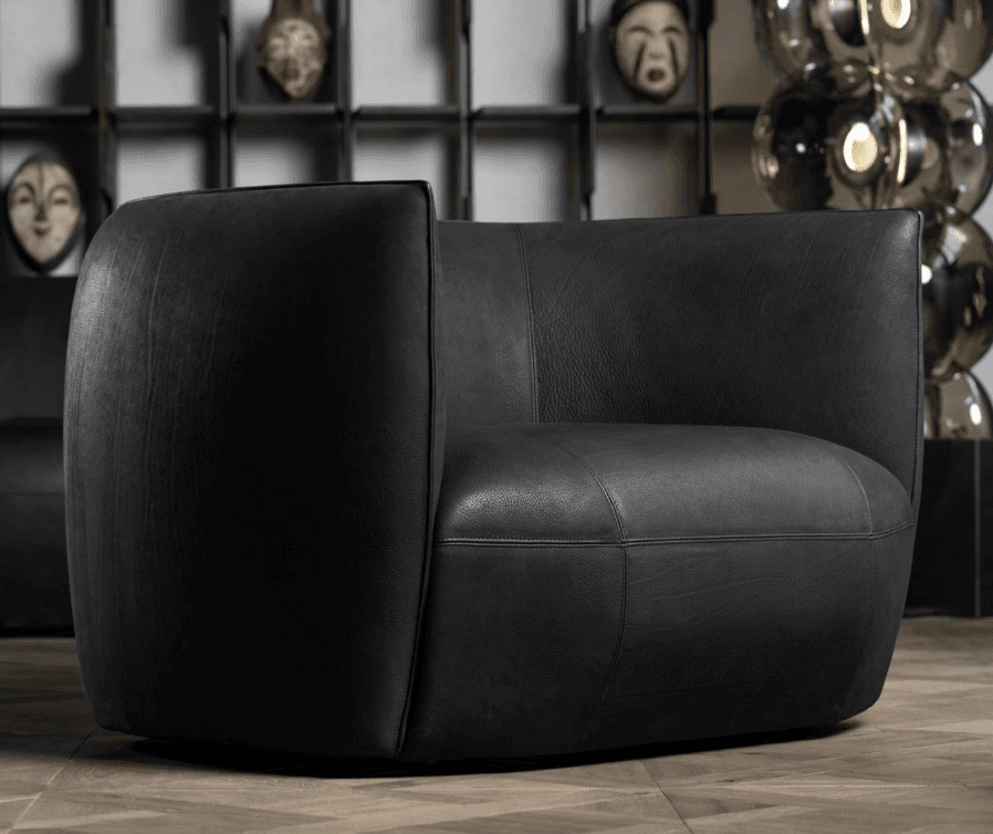 A contemporary barrel-shaped armchair upholstered in black leather, featuring a seamless design with integrated arms and a low profile. The chair exhibits a smooth, rounded silhouette and visible stitching details, suggesting quality craftsmanship. It is presented against a plain white background. — 3D model