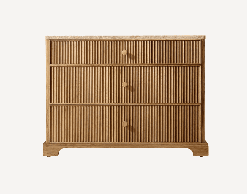 A contemporary chest of drawers featuring a fluted wood facade and a solid marble top, supported by a plinth base. It includes three generously sized drawers, each fitted with a single circular brass knob. — 3D model