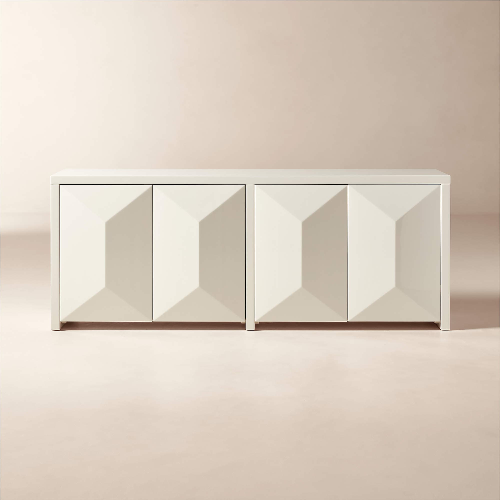 A white sideboard with a geometric, faceted design on its four doors. The doors are aligned in two pairs, creating a symmetrical facade. The sideboard has a clean, modern aesthetic with a simple rectangular silhouette and is supported by short, blocky feet. — 3D model