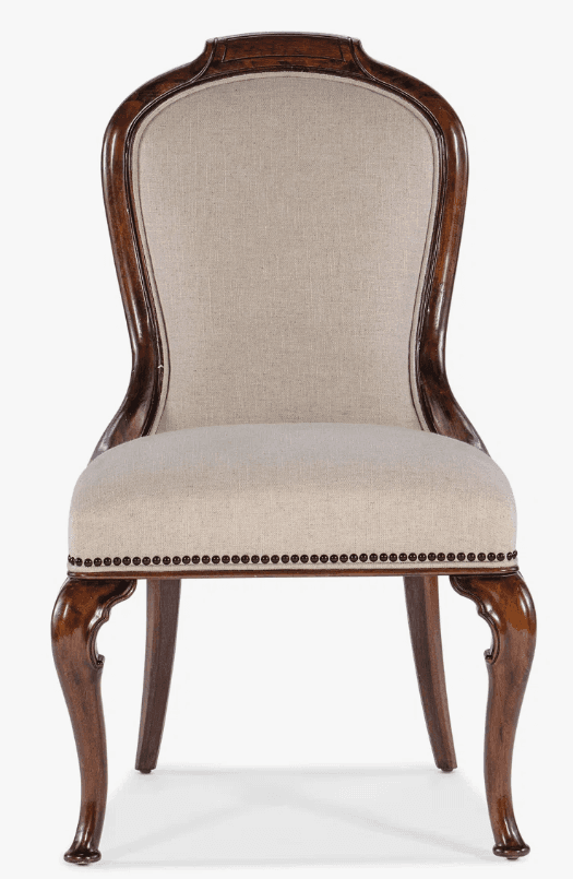 A classic armchair with a carved wooden frame and upholstered seat and back. The upholstery is a light beige linen-like fabric, tufted with decorative nailhead trim along the base of the seat cushion and the perimeter of the backrest. The wooden frame exhibits a dark brown, polished finish. The backrest has a curved, elongated shape, while the front legs feature a cabriole design with scroll details, terminating in a bulbous foot. — 3D model