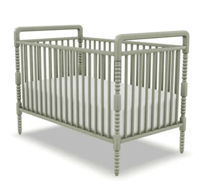 A traditional baby crib featuring vertical spindles and decorative turned posts, finished in a muted sage green color. It includes a standard white mattress. — 3D model