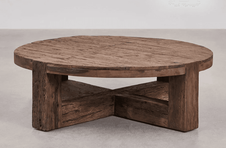 A round coffee table constructed from reclaimed wood. The tabletop is composed of multiple planks with visible grain and texture. The base features four thick, rectangular legs that are joined by intersecting wooden beams forming an 'X' shape between the legs. — 3D model