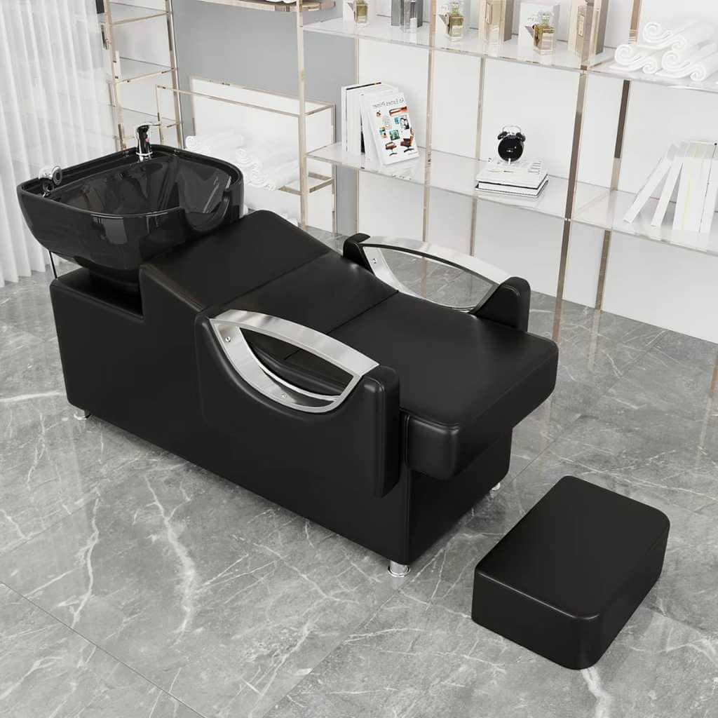 A professional salon shampoo chair with a black upholstered seat and back, an integrated black ceramic shampoo bowl, chrome faucet and sprayer, and a separate, matching black footrest. The chair features curved chrome armrests and a modern, commercial design. — 3D model