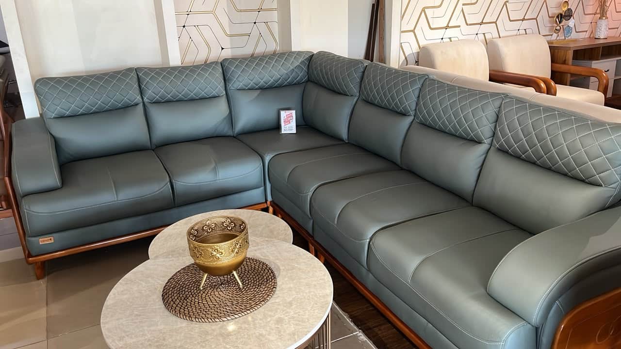 An L-shaped sectional sofa upholstered in dark gray leather, featuring distinct quilted headrests wi… — 3D model