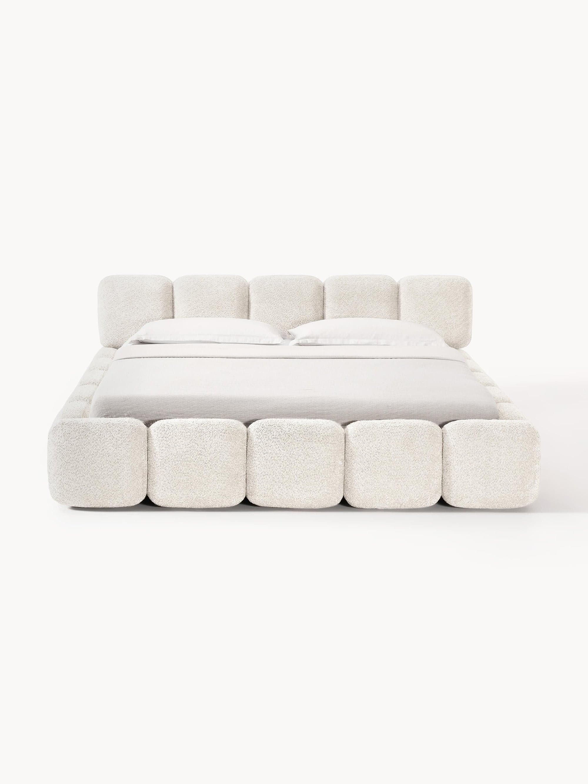 A plush, upholstered bed frame with a tufted headboard and footboard. The bed is dressed with white bedding, including two pillows. The upholstery has a textured, almost boucle-like appearance. — 3D model