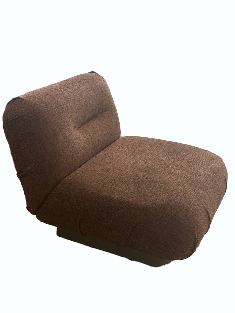 A contemporary, armless armchair with a low profile and a single padded seat and backrest. The upholstery has a textured weave. The backrest features a single button tuft in the center. It rests on a dark, flat base. — 3D model