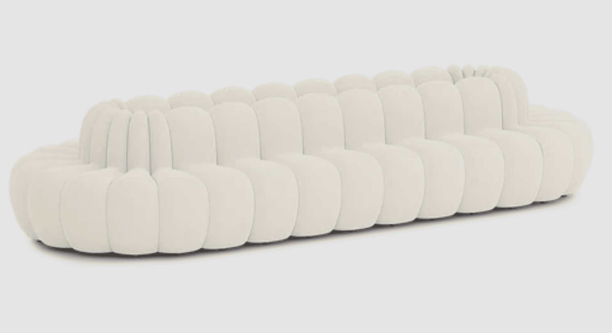 A long, contemporary sofa characterized by its distinctive bubble-like, segmented upholstery, presented in a light, neutral color. The sofa features a continuous, undulating form, with both the seat and backrest composed of individual rounded, padded elements, giving it a plush and inviting appearance. — 3D model