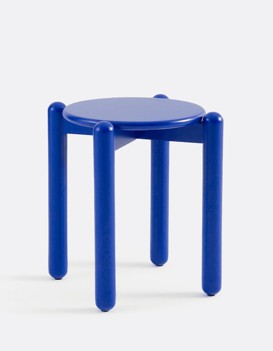 A modern, minimalist stool featuring a circular seat and four thick, cylindrical legs, all uniformly finished in a vibrant matte blue. The legs connect to the underside of the seat, extending slightly above it at the attachment points, and are capped with small protective glides at the base. — 3D model