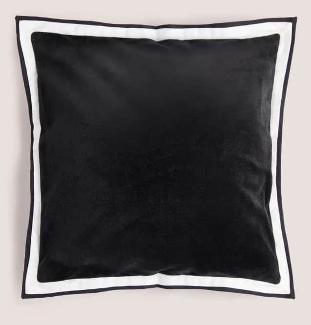 A square cushion with a plush black surface and a contrasting white and black trim around its edges.… — 3D model
