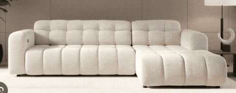 A modern, light-colored sectional sofa featuring distinct channel tufting across its seat and backrests, complete with a generously sized chaise lounge component. The design emphasizes a low profile and clean, rectilinear lines, presenting a contemporary aesthetic. — 3D model