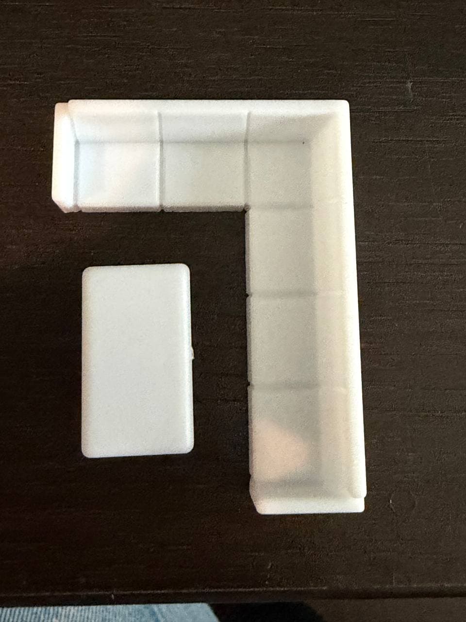 A miniature, simplified model of an L-shaped modular sectional sofa in white, paired with a matching rectangular coffee table, depicted against a white background. — 3D model