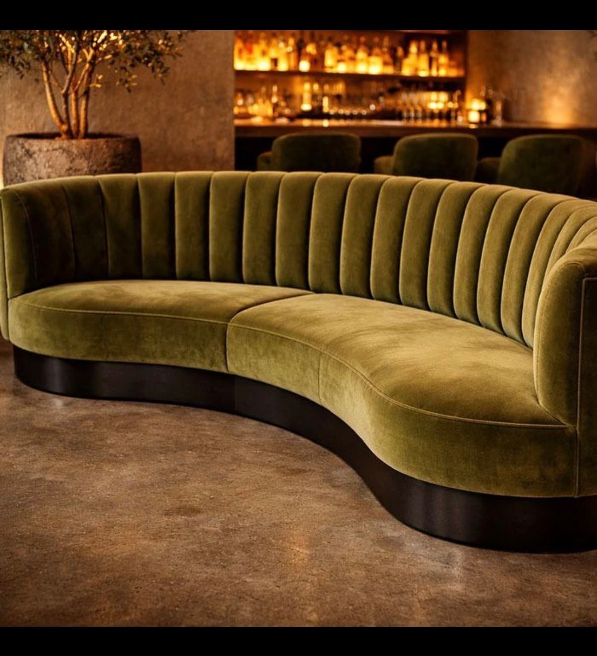 A sophisticated curved sofa upholstered in olive green velvet, featuring distinctive vertical channel tufting on the backrest. The sofa has a continuous, gracefully curved silhouette and rests on a recessed dark-finished plinth base. — 3D model