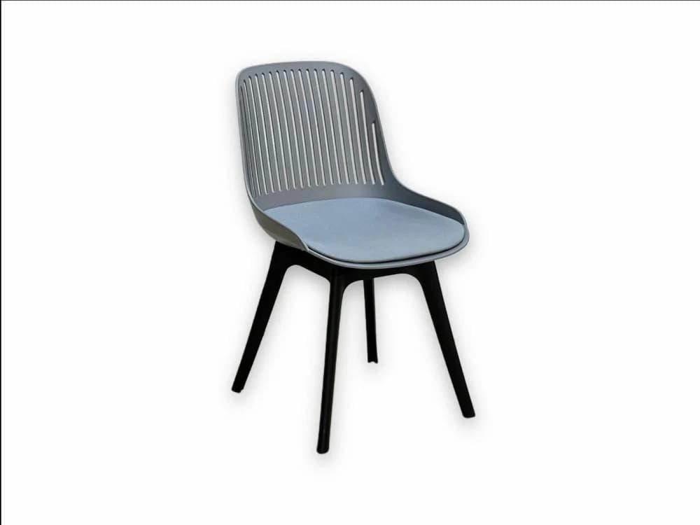 A contemporary dining chair featuring a grey molded plastic shell with a distinctive slatted back design. The seat is fitted with a light blue fabric-covered padded cushion. The chair is supported by four splayed legs finished in black. — 3D model