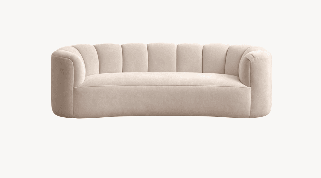 A cream-colored, upholstered sofa with a curved design and vertically channel-tufted backrest. The armrests are integrated into the body of the sofa and also feature a rounded, continuous form. The overall aesthetic suggests a modern or contemporary style with a plush texture. — 3D model