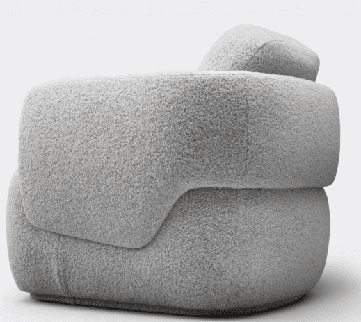 A contemporary, heavily upholstered lounge chair featuring an organic, rounded form. The chair is covered in a plush, textured boucle-like fabric in a light grey or off-white color. It has a low profile with no visible legs, appearing to sit directly on the floor or a very subtle plinth base. The backrest and armrests are integrated into the continuous, fluid shape, emphasizing comfort and softness. — 3D model