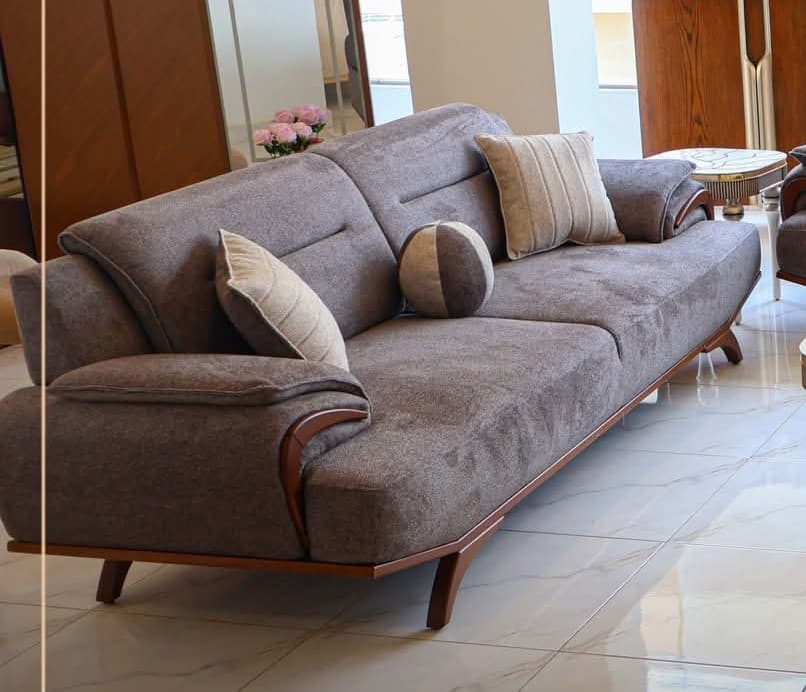 A modern two-seater sofa upholstered in grey fabric, featuring integrated armrests with dark wood accents that extend to the base. It includes two seat cushions, two back cushions, and two decorative throw pillows. — 3D model