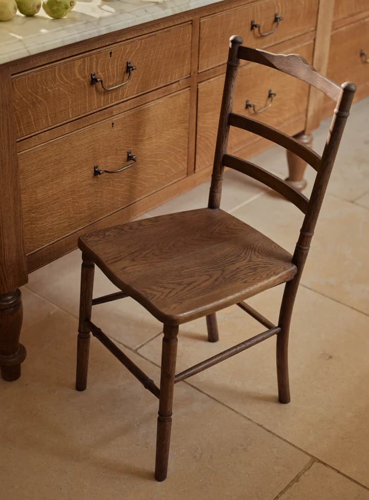 A wooden side chair with a square seat, turned legs, and a ladder-back design. The backrest features three horizontal rails and is supported by curved stiles. The chair has visible wood grain and a dark finish. — 3D model