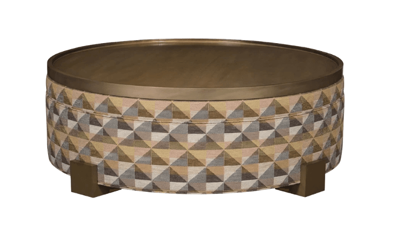 A round, upholstered ottoman featuring a geometric triangular pattern in various muted colors. It is topped with a recessed, brass-toned metal tray surface and supported by four short, brass-toned block feet. — 3D model