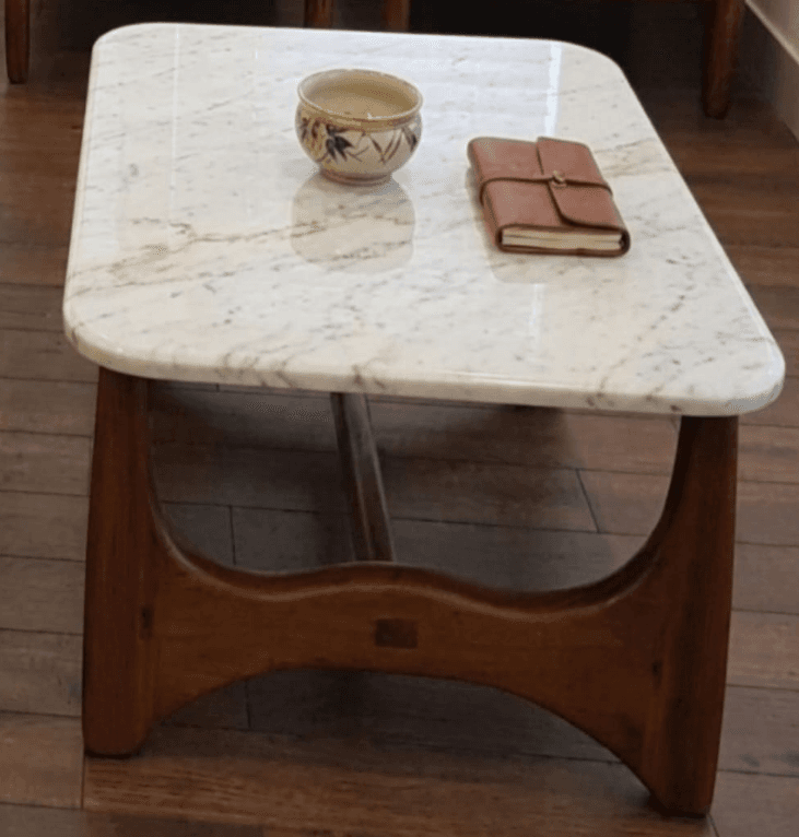 A rectangular coffee table featuring a polished white marble top with subtle grey veining. The base consists of two substantial, curved wooden supports, connected by a central, recessed wooden stretcher. The corners of the marble top are gently rounded, contributing to a refined and modern aesthetic. — 3D model