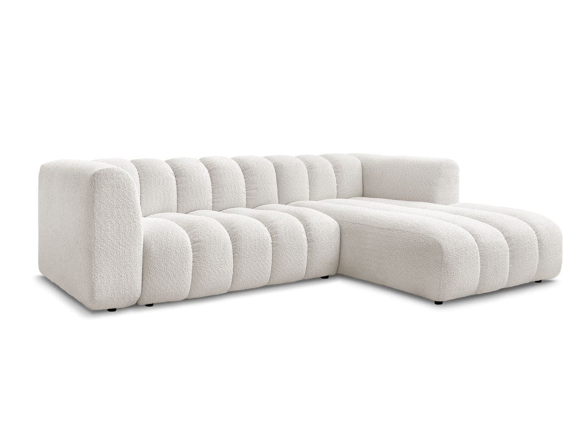 A white, modular sectional sofa with a chaise lounge extension. The sofa features a distinctive channel-tufted design on its seat cushions, backrests, and chaise. The upholstery appears to be a textured boucle fabric. The sofa has a low profile with concealed legs, giving it a contemporary aesthetic. — 3D model