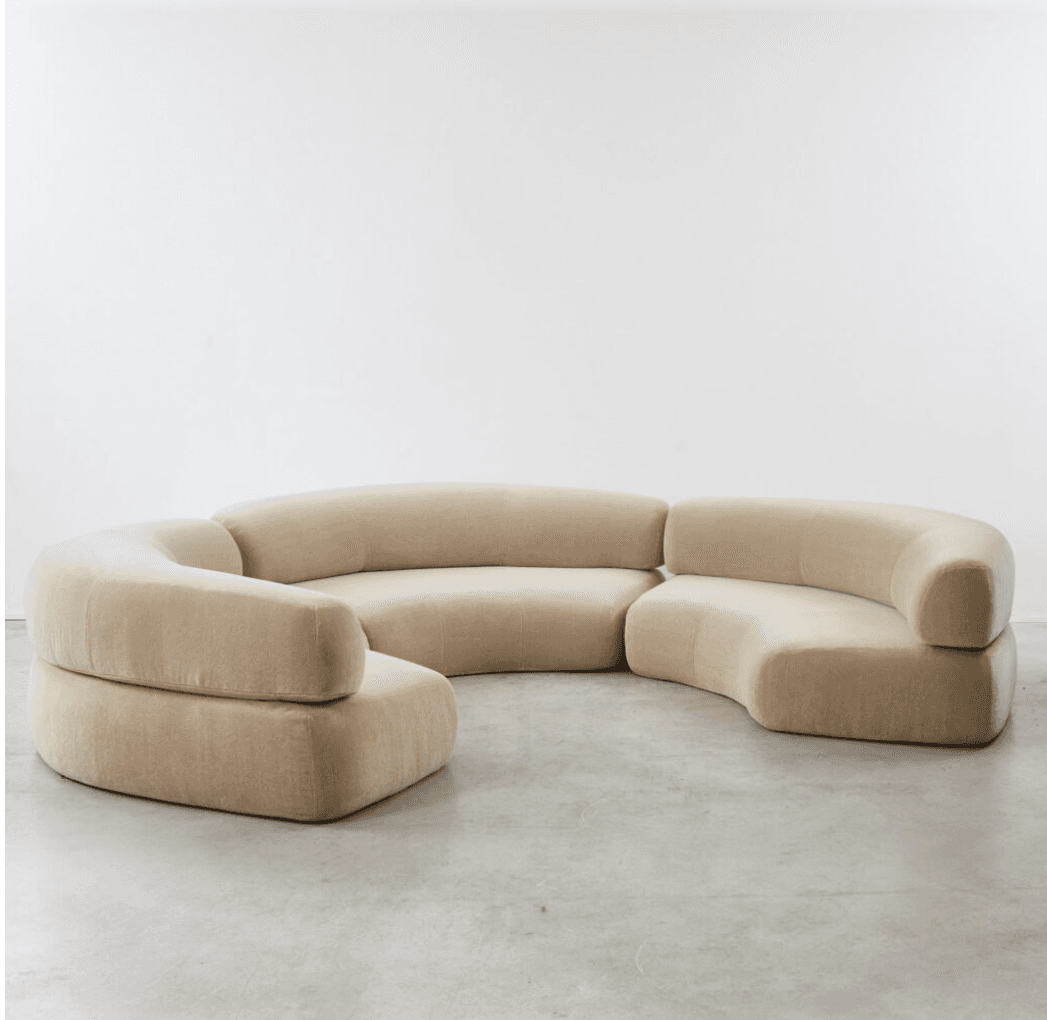 A large, modular sectional sofa with multiple curved sections, upholstered in a light beige velvet fabric, designed for flexible arrangement in a contemporary setting. — 3D model