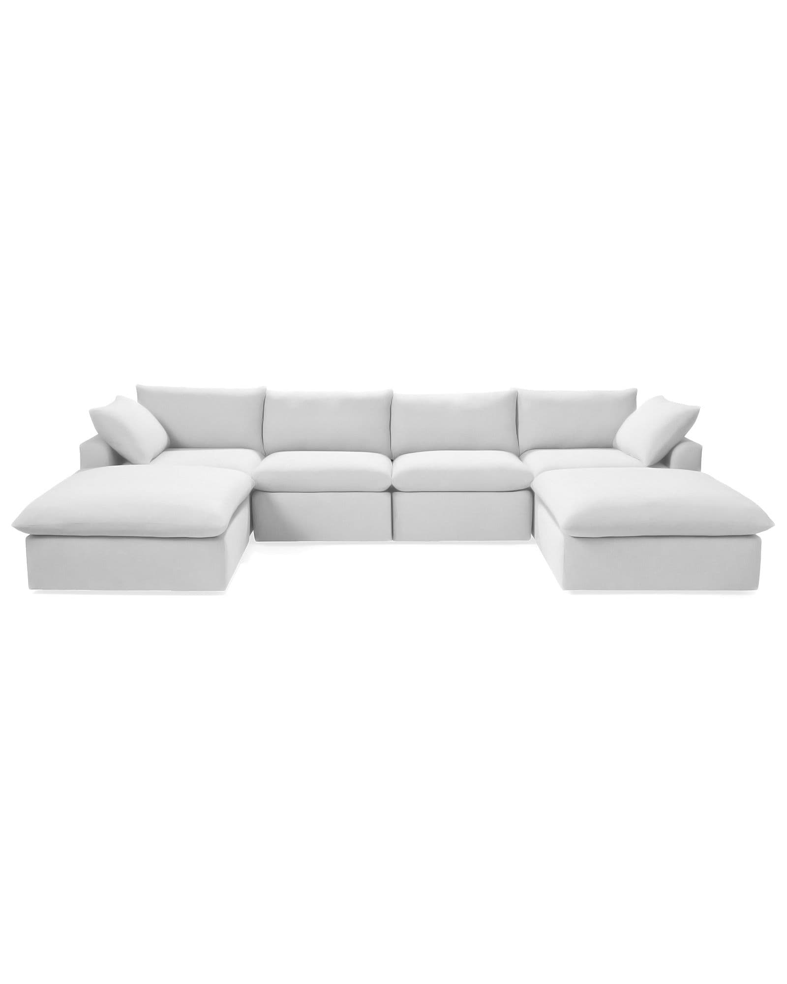A large, modular U-shaped sectional sofa upholstered in a light-colored fabric. The sofa features deep, plush cushions for the seats and backrests, with additional throw pillows. It is configured with a chaise lounge extension on each end, creating a symmetrical design. The base of the sofa is a solid, low-profile frame. — 3D model